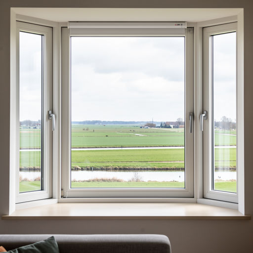 blik vanuit woonkamer in Coevorden door wit kunststof erkerraam over landelijk gebied
